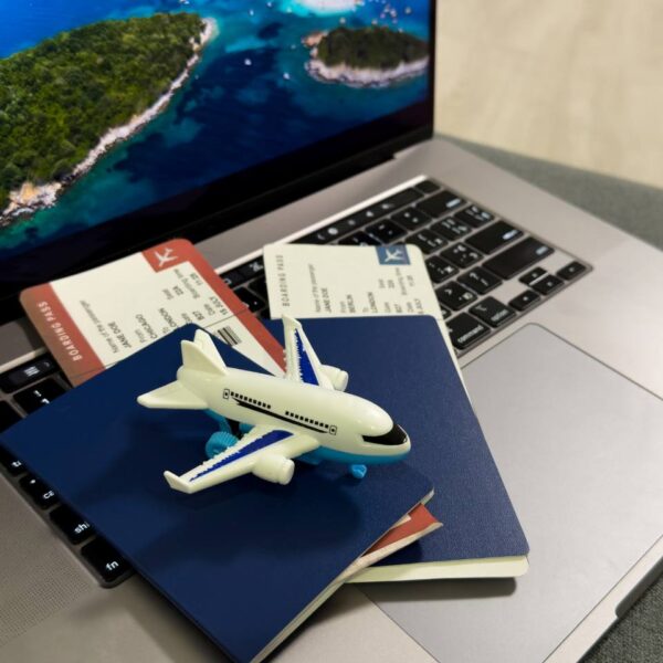 toy airplane on top of passports, plane tickets and a laptop