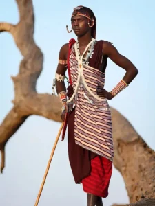 Maasai tribesman standing near the reflective waters of Lake Natron, with Ol Doinyo Lengai in the background