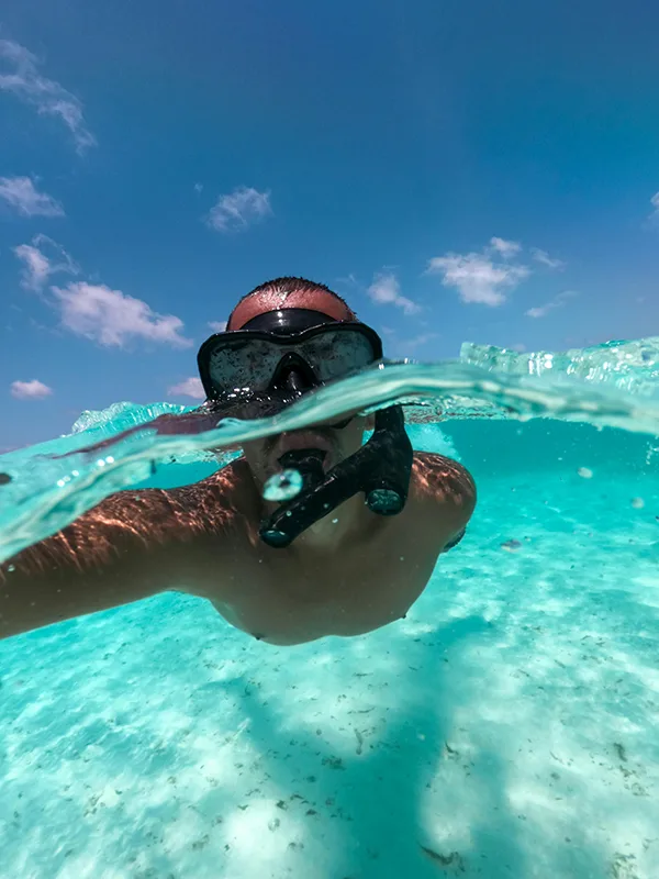 A snorkeler swimming above vibrant coral reefs and tropical fish at Mafia Island, Tanzania