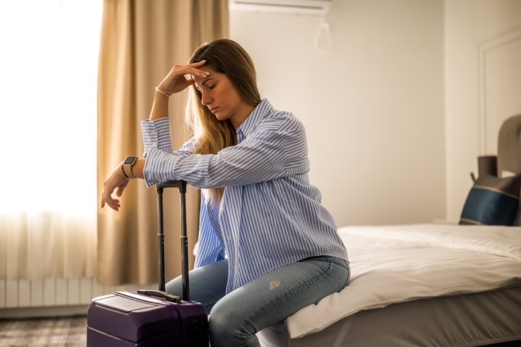 exhausted woman is waiting for her flight in hotel room