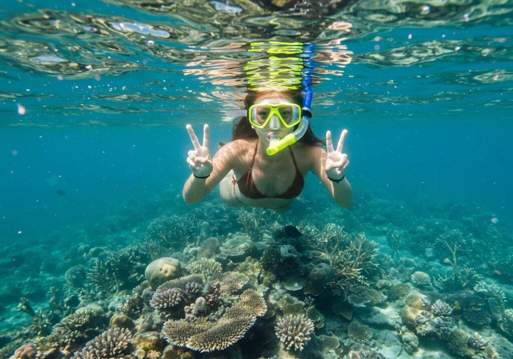 Snorkeler Flashes Double Peace Signs Above a Vibrant Coral Reef