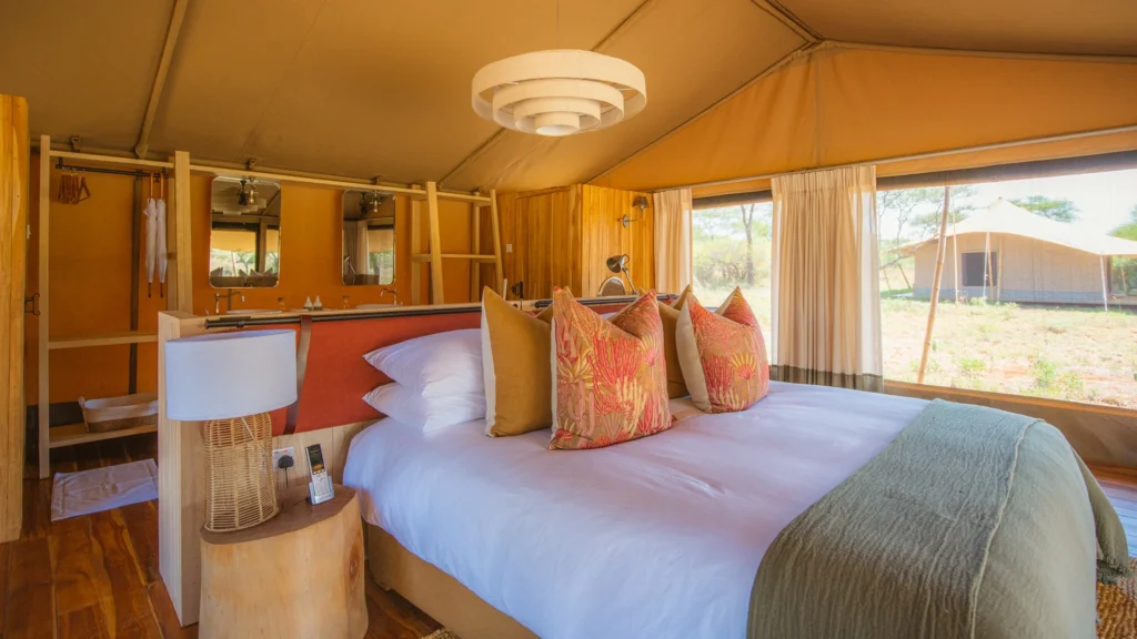 Spacious luxury safari tent interior in Tanzania with elegant furnishings and comfortable bedding