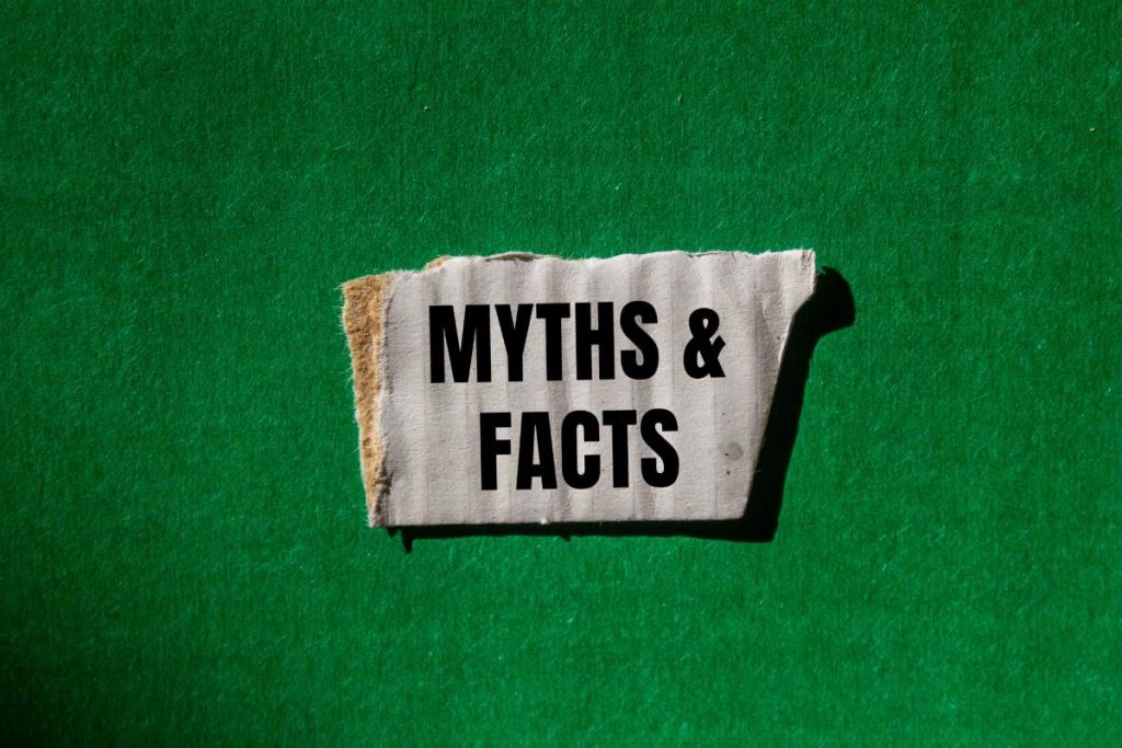 Myths and facts message written on ripped torn white paper piece with green background