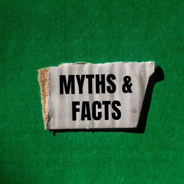 Myths and facts message written on ripped torn white paper piece with green background