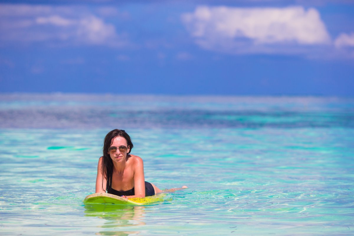 Young surfer woman surfing during beach vacation