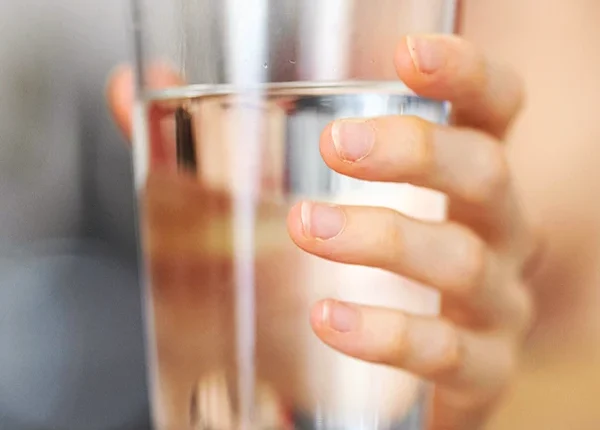 The hand holding a glass of clean water