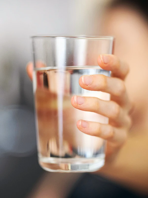 The hand holding a glass of clean water exhibiting public health training & education empowering.