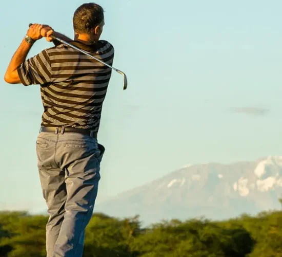 Golfer teeing off at Kilimanjaro Golf Course with Mount Kilimanjaro in the background during a luxury Tanzania safari