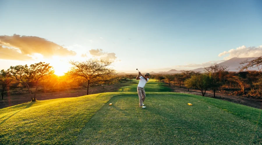 Golfer playing at sunset on a scenic golf course in Tanzania during a luxury safari and golf experience